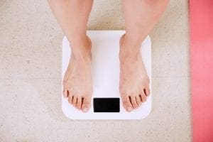 person weighing herself with scale